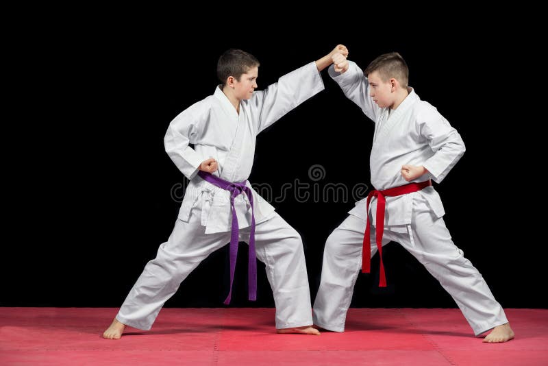 Dos muchachos en la lucha blanca del kimono aislados en fondo negro imagen de archivo Dos muchachos en la lucha blanca del kimono aislados en fondo negro imagen de archivo