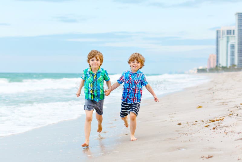 Dos muchachos felices de los niños que corren en la playa del océano Niños, hermano divertido y mejores amigos lindos haciendo va imágenes de archivo libres de regalías Dos muchachos felices de los niños que corren en la playa del océano Niños, hermano divertido y mejores amigos lindos haciendo va imágenes de archivo libres de regalías