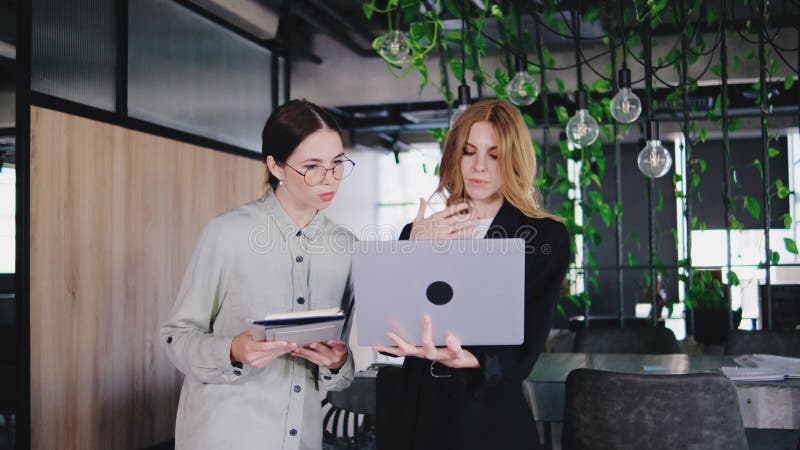 Dos mujeres altamente profesionales participan activamente en un debate empresarial productivo y perspicaz dentro de un almacen de video