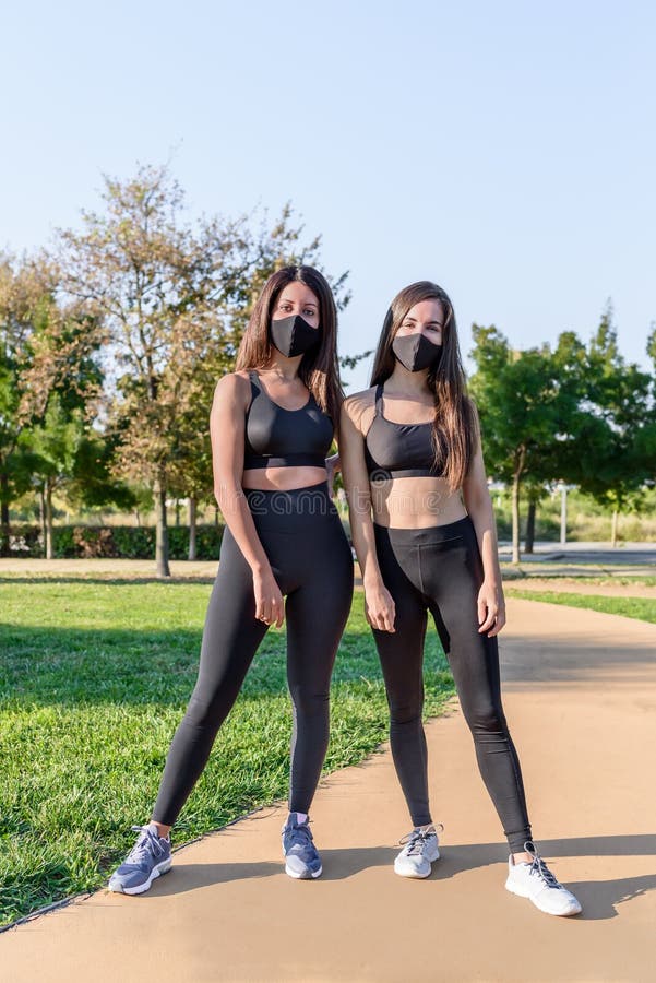 Dos Mujeres Con Ropa Deportiva Y Máscara Negra Posando Para Una Foto En Un Parque Verde Imagen de - Imagen de amistad, oscuro: 196712265