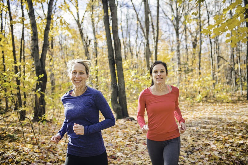 Dos mujeres corriendo trotando en la naturaleza otoñal foto de archivo libre de regalías