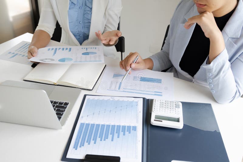 Dos mujeres del líder empresarial que discuten las cartas y los gráficos que muestran los resultados imagenes de archivo Dos mujeres del líder empresarial que discuten las cartas y los gráficos que muestran los resultados imagenes de archivo
