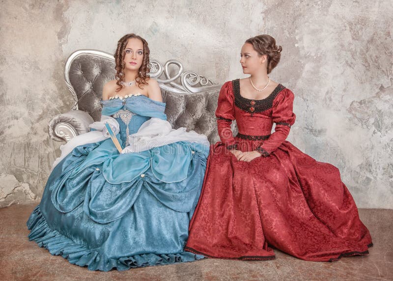 Dos Mujeres Hermosas En Vestidos Medievales En El Sofá Imagen de