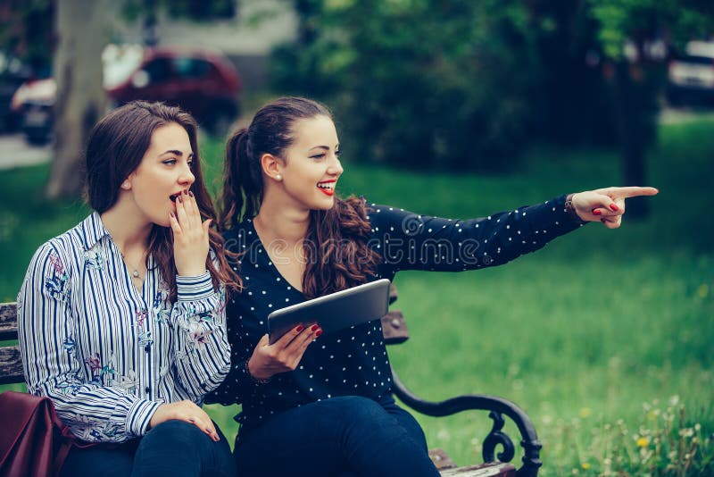 Dos mujeres hermosas que sostienen una tableta que señala lejos en la calle fotos de archivo libres de regalías Dos mujeres hermosas que sostienen una tableta que señala lejos en la calle fotos de archivo libres de regalías
