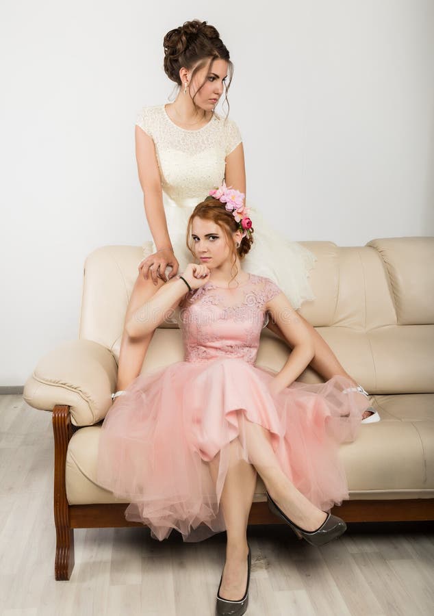 Dos Mujeres Jovenes Encantadoras En Los Vestidos Elegantes Que Se Sientan  En Un Sofá, Historia Blanda Foto de archivo - Imagen de grupo, amigos:  121371052