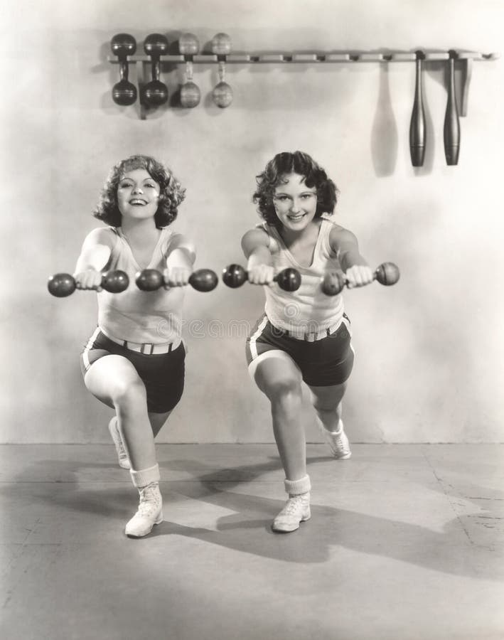 Dos mujeres que ejercitan con pesas de gimnasia en el gimnasio