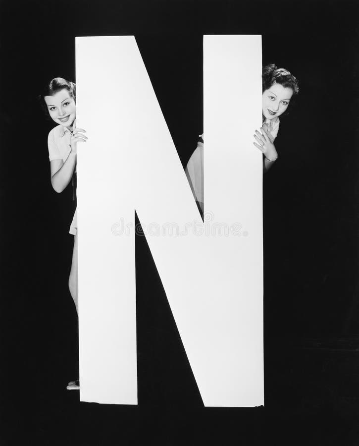 Dos mujeres que ocultan detrás de la letra enorme N (todas las personas representadas no son vivas más largo y ningún estado exis