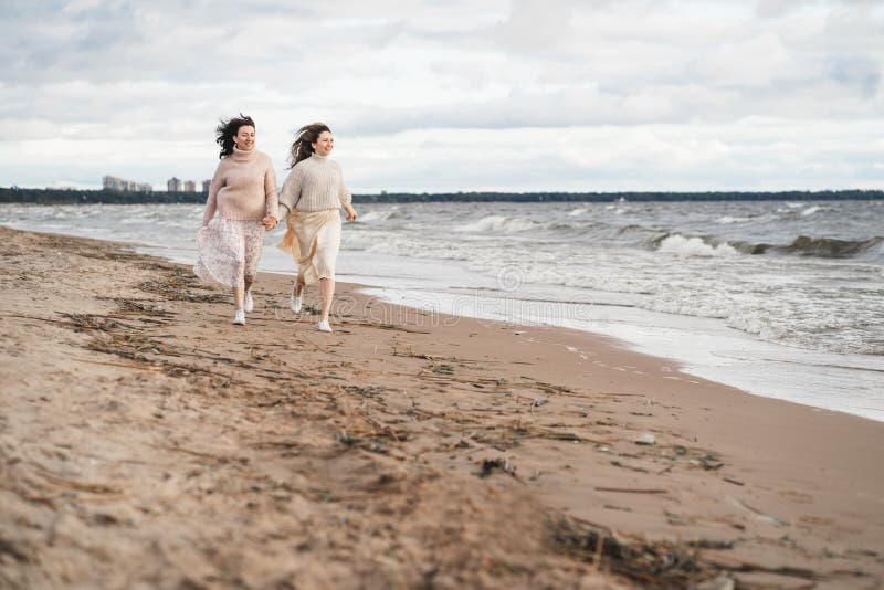 Dos niñas cogen de la mano y corren a lo largo de la costa. las hermanas se divierten juntas. una pareja enamorada en una cita. ot foto de archivo