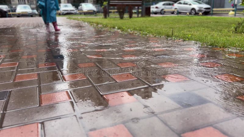 Dos niños con impermeables amarillos y azules y botas corriendo a través de un charco en un día lluvioso. hermanos felices metrajes