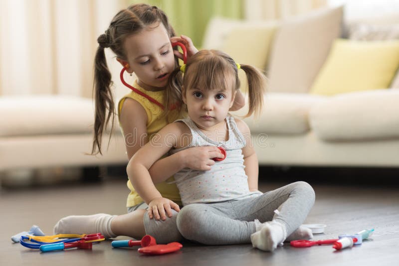 Dos niños del preescolar, niña pequeña linda y su más vieja hermana del niño, jugando el doctor y el hospital usando el juguete y fotos de archivo Dos niños del preescolar, niña pequeña linda y su más vieja hermana del niño, jugando el doctor y el hospital usando el juguete y fotos de archivo