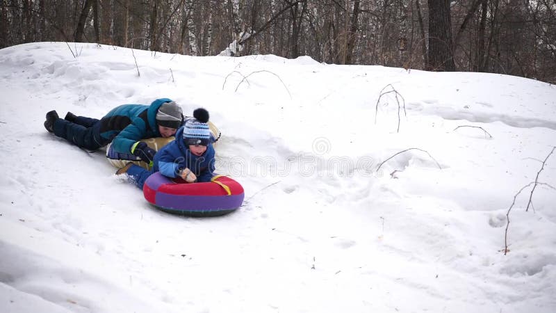 Dos niños montan en una colina nevosa en un trineo Caída de los niños con un trineo Deportes y actividades al aire libre