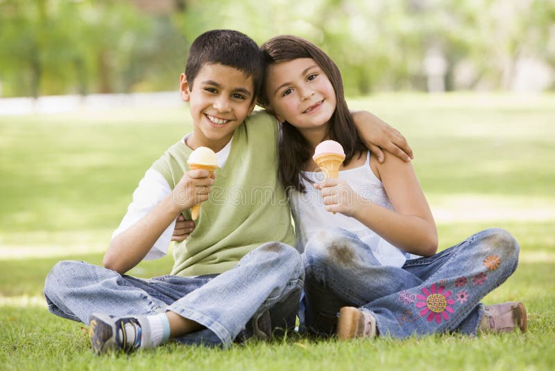 Dos niños que comen el helado en parque foto de archivo