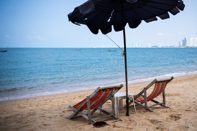 Dos ociosos y un paraguas en el mar azul en la playa de Pattaya, Tailandia Visión posterior imagen de archivo libre de regalías Dos ociosos y un paraguas en el mar azul en la playa de Pattaya, Tailandia Visión posterior imagen de archivo libre de regalías