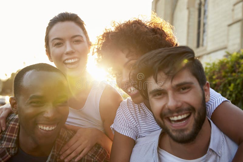 Dos pares adultos jovenes felices que llevan a cuestas la calle fotografía de archivo Dos pares adultos jovenes felices que llevan a cuestas la calle fotografía de archivo