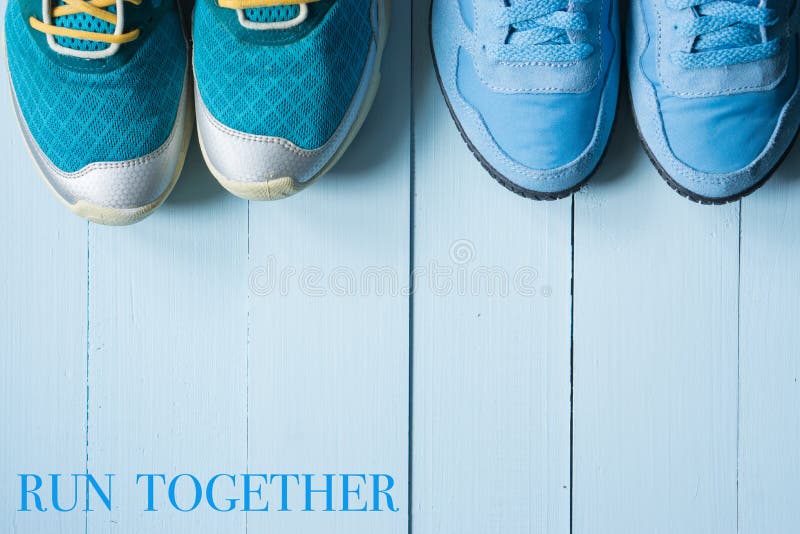 Two pairs of running sneakers on blue background. with inscription sign. run together. clean sport concept. blue wooden background. Two pairs of running sneakers on blue background. with inscription sign. run together. clean sport concept. blue wooden background