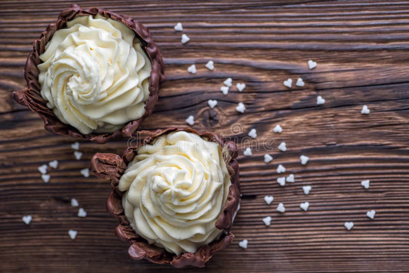 Dos postres del chocolate llenaron de la crema blanca en la tabla de madera, postre con los corazones blancos para el día de tarj fotos de archivo Dos postres del chocolate llenaron de la crema blanca en la tabla de madera, postre con los corazones blancos para el día de tarj fotos de archivo