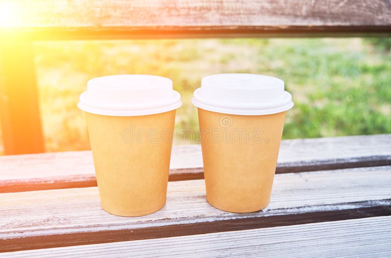 Dos Tazas De Café Para Llevar En El Parque En Un Banco De Madera a