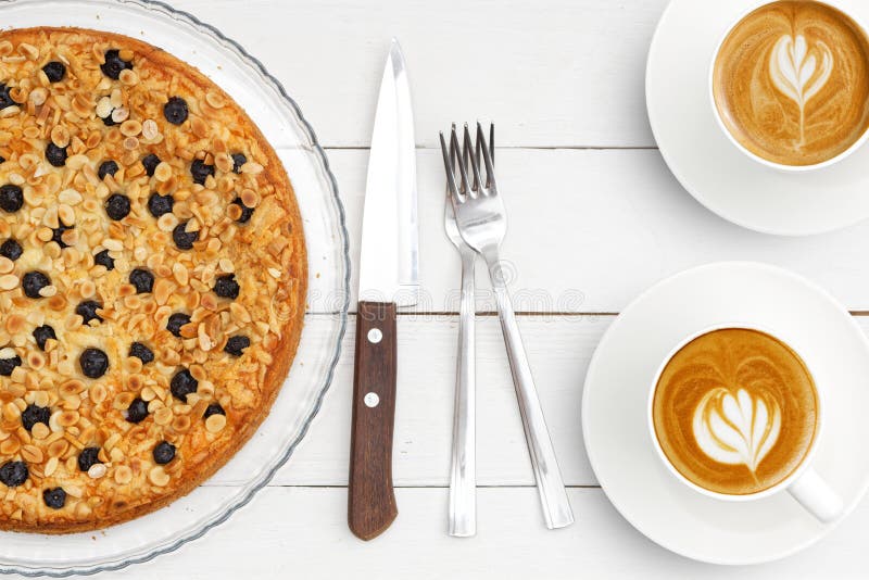 Dos tazas de café y de empanada hecha en casa con el soplo del requesón adornado con las almendras y los arándanos en la tabla de foto de archivo libre de regalías Dos tazas de café y de empanada hecha en casa con el soplo del requesón adornado con las almendras y los arándanos en la tabla de foto de archivo libre de regalías