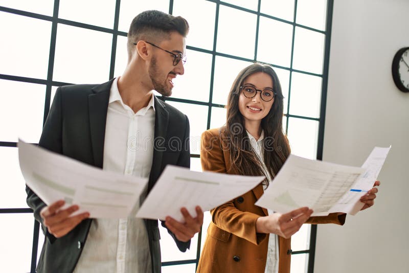 Dos trabajadores de negocios sonrientes y alegres papeles de lectura en la oficina fotos de archivo