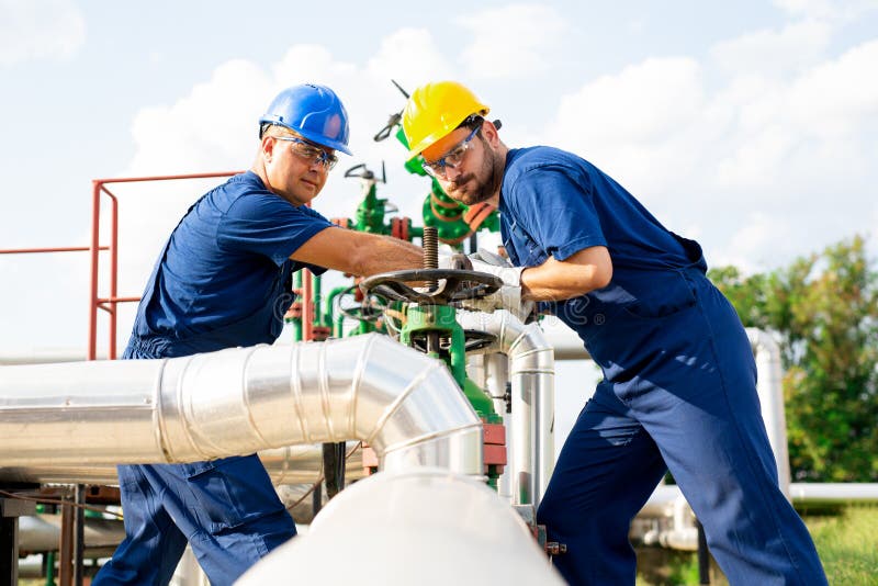 Dos trabajadores petroquímicos que examinan las válvulas de presión en un depósito de gasolina fotos de archivo Dos trabajadores petroquímicos que examinan las válvulas de presión en un depósito de gasolina fotos de archivo