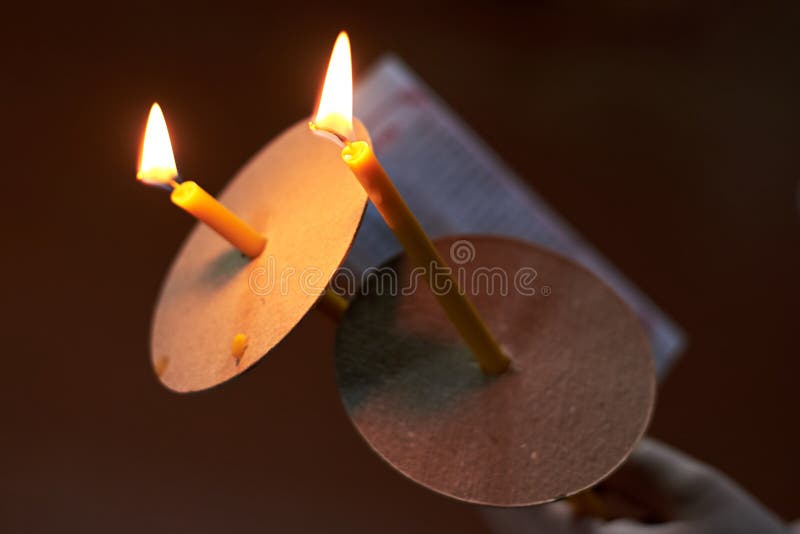 Dos velas de la iglesia y una hoja del rezo en la mano en un fondo oscuro foto de archivo Dos velas de la iglesia y una hoja del rezo en la mano en un fondo oscuro foto de archivo