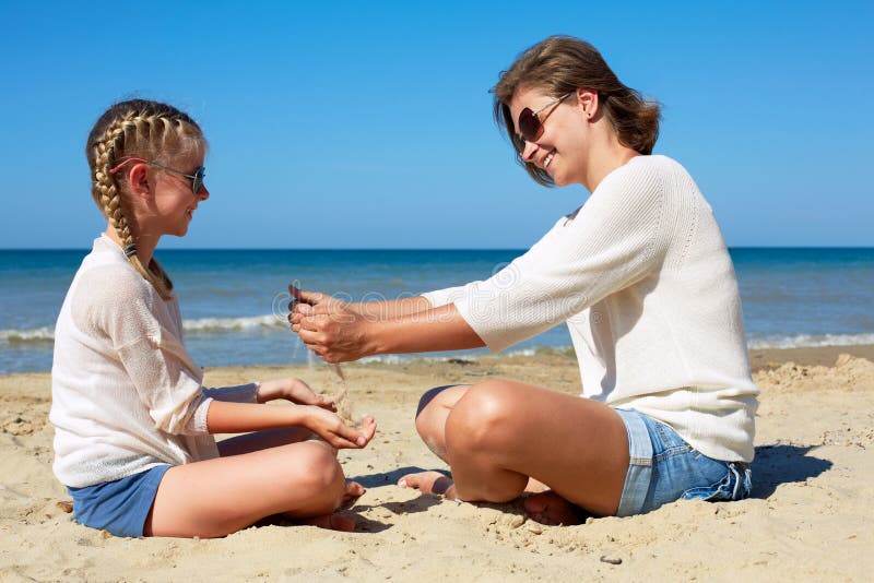 Dotter och hennes mamma som spelar med sand p? stranden