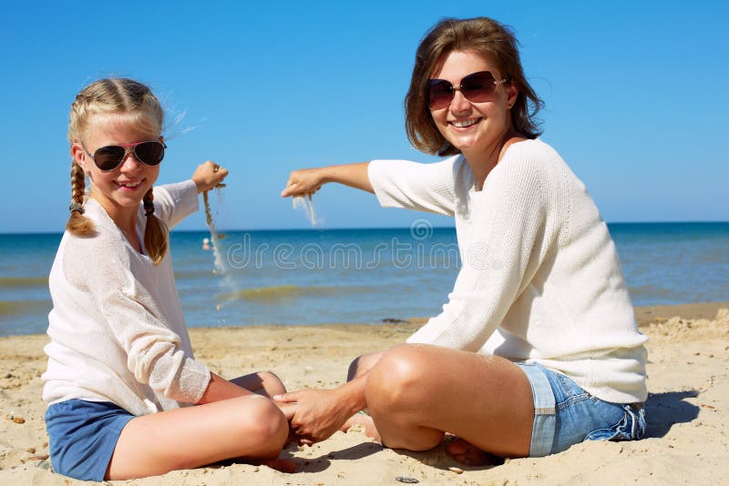 Dotter och hennes mamma som spelar med sand p? stranden