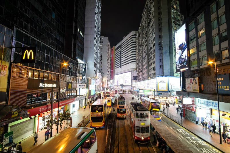 Double decker buses drive on the road of Causeway Bay on a rainy evening royalty free stock images