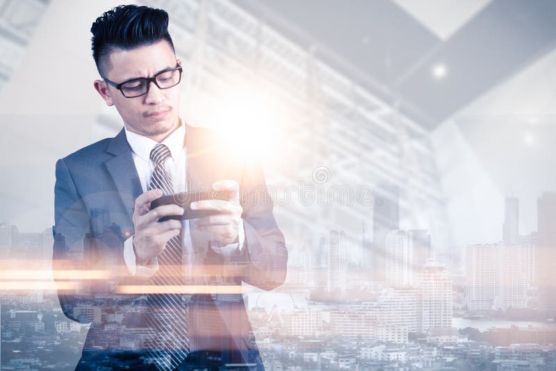 The double exposure image of the businessman using or a smartphone or play a game during sunrise overlay with cityscape image. royalty free stock images