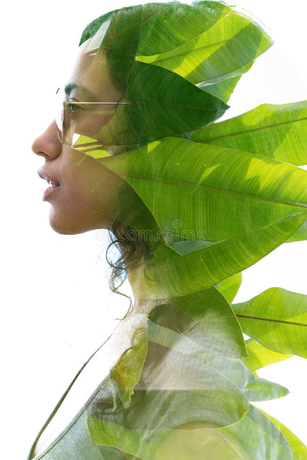 A double exposure portrait of a young woman profile with sun glasses against white background with large tropical leaves