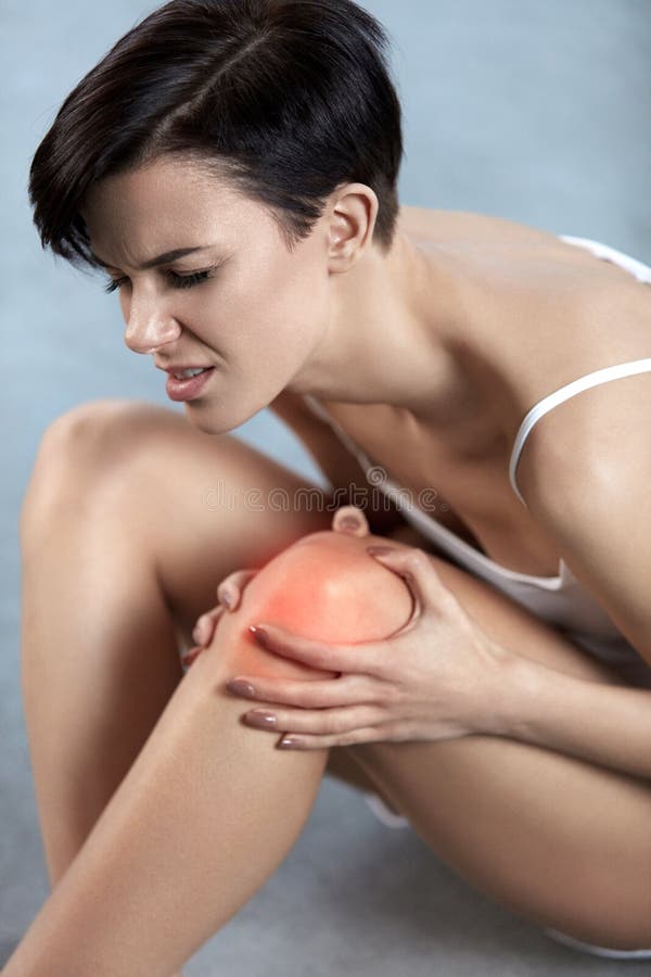 Douleur de corps Belle femme avec le genou douloureux, douleur dans la jambe se sentante photographie stock Douleur de corps Belle femme avec le genou douloureux, douleur dans la jambe se sentante photographie stock