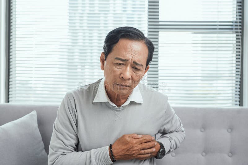 Douleur de sensation de vieil homme à leur coeur dans le salon, concept médical photos libres de droits Douleur de sensation de vieil homme à leur coeur dans le salon, concept médical photos libres de droits