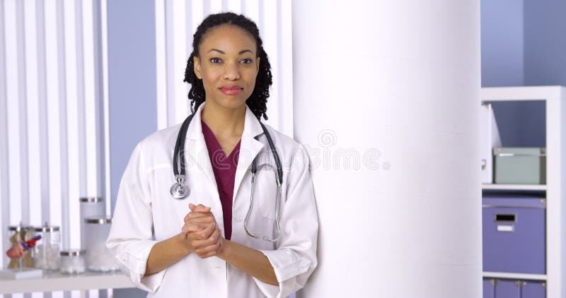 Doutor amigável da mulher negra que está no escritório foto de stock Doutor amigável da mulher negra que está no escritório foto de stock