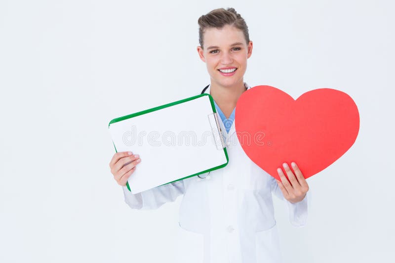 Doutor feliz que guarda o cartão da prancheta e do coração foto de stock Doutor feliz que guarda o cartão da prancheta e do coração foto de stock