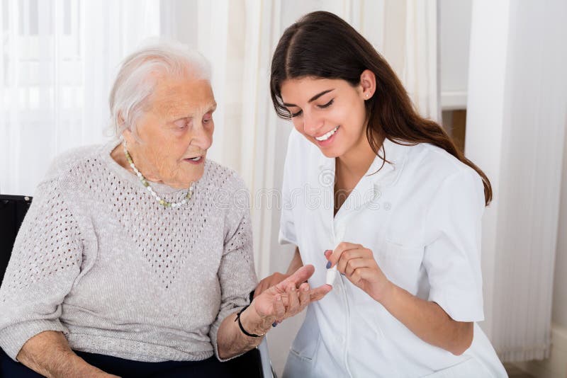 Happy Female Doctor Checking Blood Sugar Level Of Senior Patient With Glucometer In Clinic. Happy Female Doctor Checking Blood Sugar Level Of Senior Patient With Glucometer In Clinic