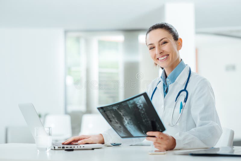 Doutor fêmea de sorriso que examina um raio X imagens de stock Doutor fêmea de sorriso que examina um raio X imagens de stock