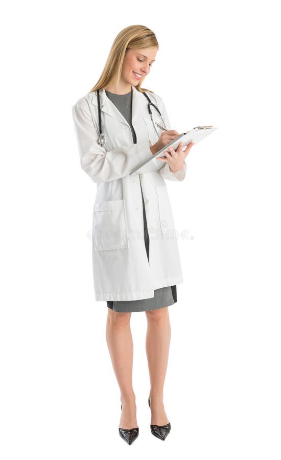 Médica sorrindo enquanto escreve na prancheta foto de stock royalty free