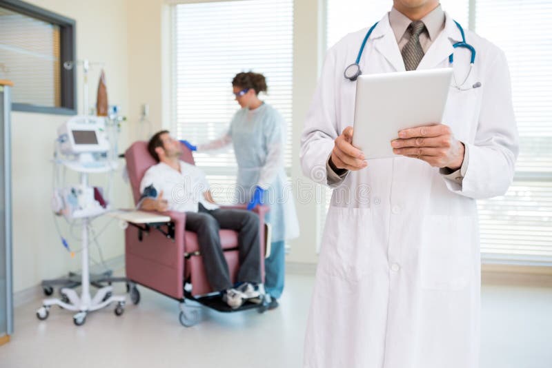 Doutor Holding Digital Tablet em Chemo Room fotografia de stock Doutor Holding Digital Tablet em Chemo Room fotografia de stock