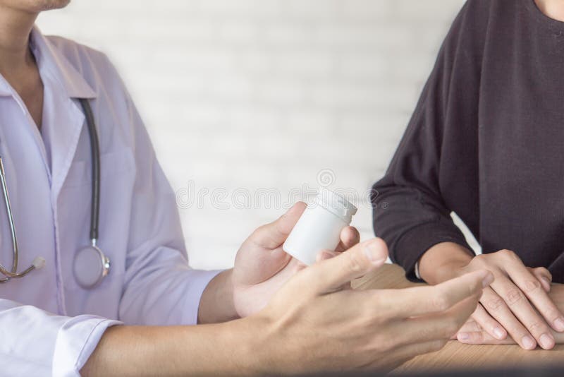 Doutor masculino que dá a garrafa da medicina ao paciente fêmea em um hospital imagens de stock Doutor masculino que dá a garrafa da medicina ao paciente fêmea em um hospital imagens de stock