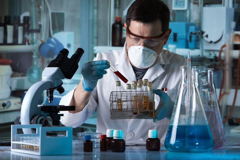 Doutor que guarda o tubo e a bandeja de análise de sangue com as amostras de urina de pacientes no laboratório da análise imagem de stock Doutor que guarda o tubo e a bandeja de análise de sangue com as amostras de urina de pacientes no laboratório da análise imagem de stock