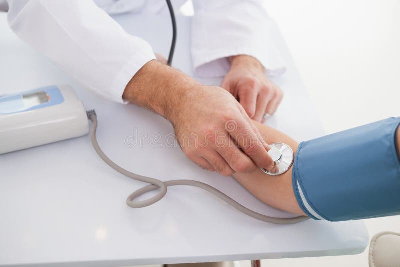 Médico a medir a pressão arterial ao paciente imagem de stock