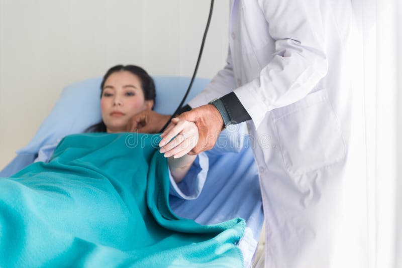 Doutor que usa o estetoscópio ao paciente da mulher para a frequência cardíaca de escuta no leito do enfermo no hospital, mão do imagens de stock royalty free Doutor que usa o estetoscópio ao paciente da mulher para a frequência cardíaca de escuta no leito do enfermo no hospital, mão do imagens de stock royalty free