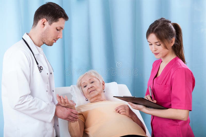 Doutores que diagnosticam a mulher idosa imagem de stock royalty free Doutores que diagnosticam a mulher idosa imagem de stock royalty free