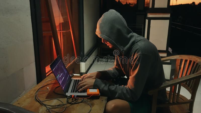 Downshifter Hacker-Programmierer in einer Kapuze erstellt ein neues Programm mit Viren. ein Anfänger-Programmierer arbeitet an stockfoto