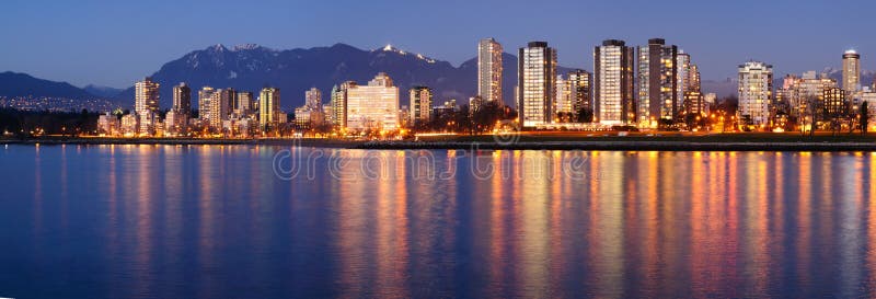 Downtown Vancouver on a winter evening glows in the dusk against a backdrop of majestic mountains. Vancouver skyscraper stock images, royalty-free photos and pictures