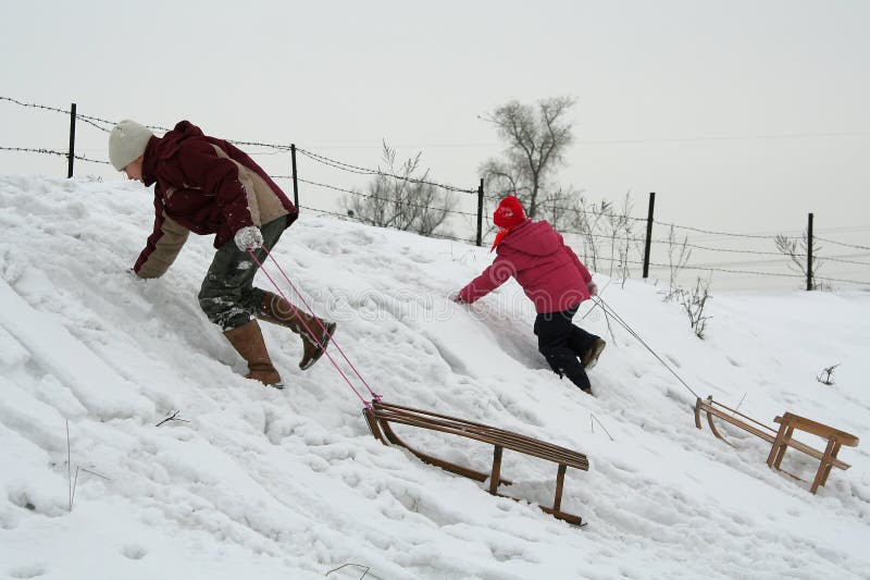 Two children pulling their sleds. Two children pulling their sleds