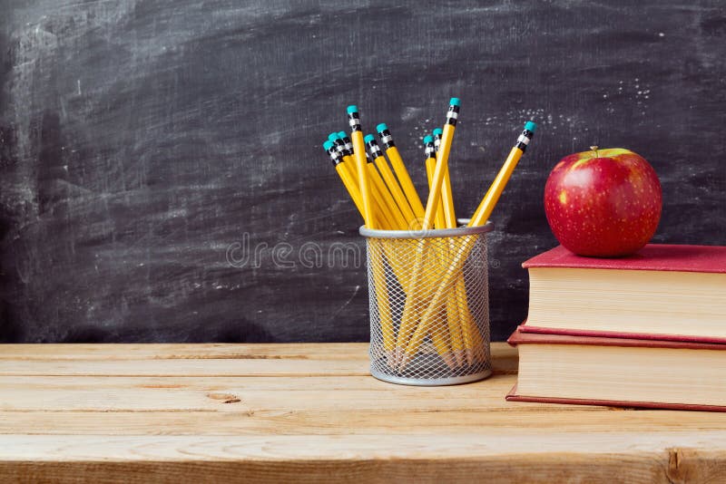 Dra tillbaka till skolabakgrund med böcker, blyertspennor och äpplet över den svart tavlan