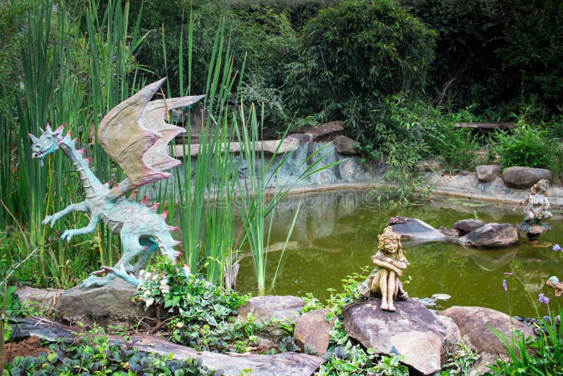 Drago decorativo e statue leggiadramente che si siedono sul bordo dello stagno in b fotografia stock libera da diritti Drago decorativo e statue leggiadramente che si siedono sul bordo dello stagno in b fotografia stock libera da diritti