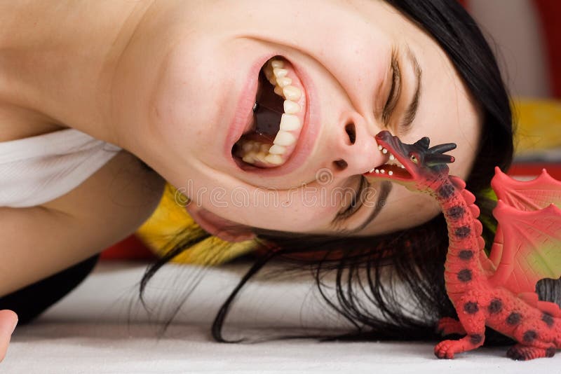 Portrait of a girl attacked by the dragon toy. Smiling dragon stock images, royalty-free photos and pictures