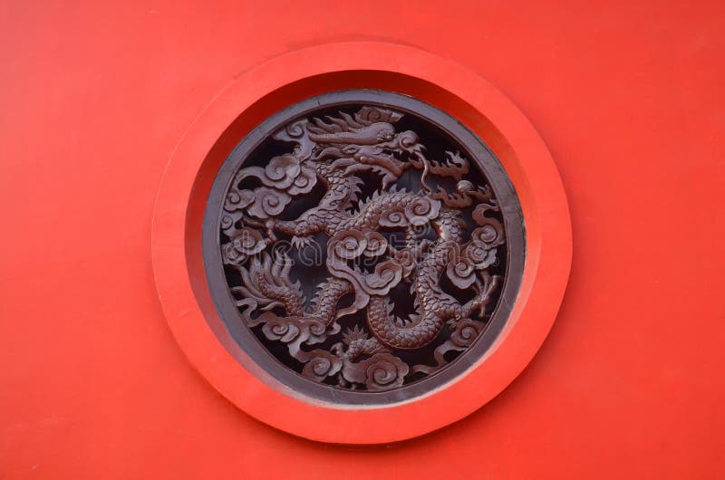 Dragon découpé en bois en cercle sur le fond rouge dans le temple chinois de bouddhisme dans Lumbini, Népal photographie stock libre de droits Dragon découpé en bois en cercle sur le fond rouge dans le temple chinois de bouddhisme dans Lumbini, Népal photographie stock libre de droits
